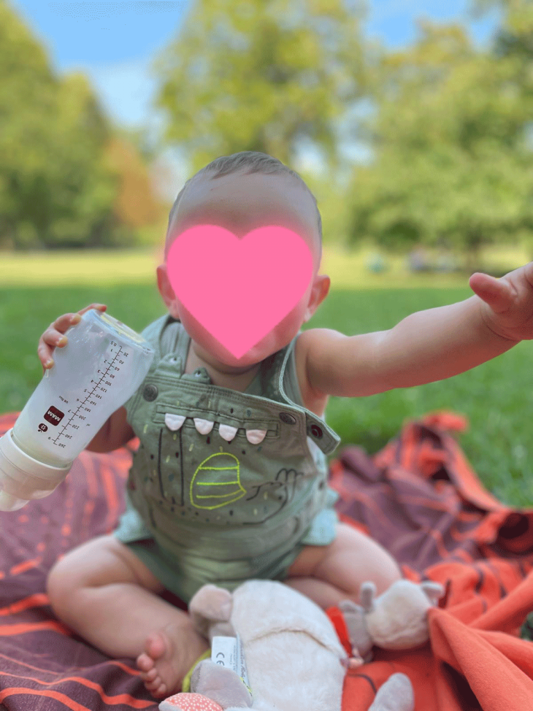 Bébé qui boit son biberon au parc